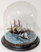 A diorama of three ships off the coast with lighthouse under a glass dome.