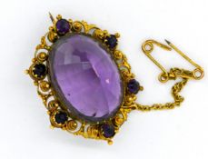 An antique amethyst brooch, with a central amethyst surrounded by smaller amethysts in a filigree