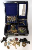 A collection of costume jewellery in a lacquered jewellery box, to include brooches, chains,