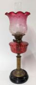 A 19th century pink glass oil lamp, brass with ebonised base, height approx 66cm.