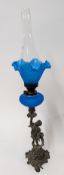 An elaborate blue glass oil lamp on a metal base stylised as a putto figure, height approx 51cm.