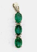 A three stone emerald pendant set with four small diamonds inbetween, set in 9ct white gold,