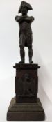 A bronze figure of Napoleon standing, arms crossed, on a plinth base decorated with Imperial