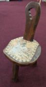 A small rustic three legged chair with painted leather seat depicting a man on horseback, height