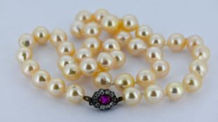 A baroque pearl necklace with ruby & diamond clasp, a string of knotted baroque shaped pearls set to