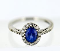An 18ct white gold tanzanite and diamond cluster ring, claw set to the centre with an oval-cut