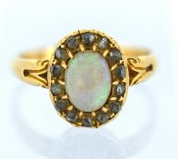An 18ct gold opal and diamond cluster ring, claw set with an oval opal cabochon with a surround of