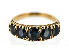 A five stone sapphire ring, claw set with five graduated oval-cut dark blue sapphires, scroll carved