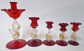 A collection of red glass candlesticks, of various sizes, with moulded glass fish and swan