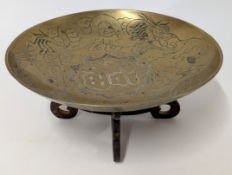 An oriental brass bowl engraved with dragon motif complete with wooden stand.