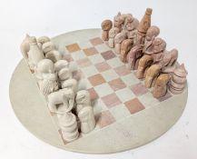 A carved soapstone complete chess set, board diameter approx 40cm.