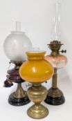 Three 19th century oil lamps of globular form, with brass and ebonised bases. (3)