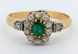 An Edwardian emerald and diamond cluster ring, claw set with an oval-cut emerald with a surround