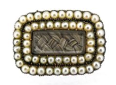 A Georgian hairwork and pearl mourning brooch, a lock of plaited hair under a central glass panel