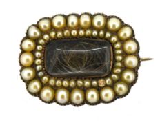 A Georgian hairwork and pearl mourning brooch, a lock of hair under a central glass panel with a