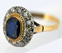 A sapphire and diamond cluster ring, collet set with an oval-cut sapphire, with a surround of