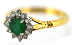 An 18ct gold emerald and diamond cluster ring, claw set with a circular-cut emerald, surmounted by
