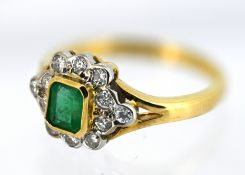 An 18ct gold emerald and diamond cluster ring, collet set with an emerald-cut emerald, with a