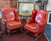 A pair of leather winged armchairs, with stud upholstery and mahogany feet.