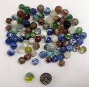 A collection of glass marbles, including a larger marble in a latticinio core swirl-style.