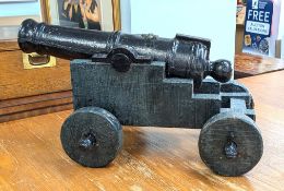 A late 18th/early 19th century iron cannon on a wooden frame with wheels, length approx. 54cm.