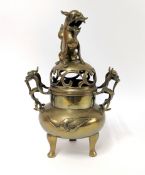 A Chinese bronze censer with twin mythical creature handles and a pierced domed cover with dragon