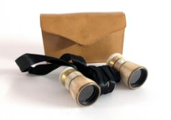 A small pair of mother of pearl opera glasses in a leather case.