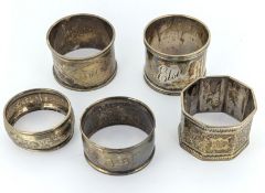 An assortment of five silver napkin rings with engraved decoration