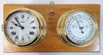 A brass clock and barometer mounted on wood.
