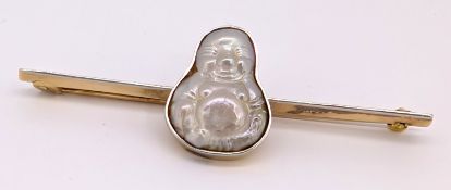 An antique Buddha carved blister pearl brooch, the bar brooch collet set with a carved blister pearl