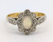 An Edwardian opal and diamond cluster ring, milgrain set with an oval-cut opal cabochon with a