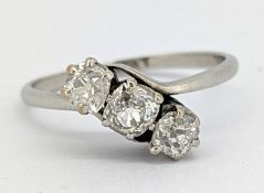 An antique three stone cross-over ring, claw set with three old-cut diamonds, slightly cushion-cut