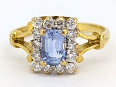 An 18ct gold sapphire and diamond cluster ring, claw set with a rectangular-cut pale blue