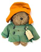 A Paddington bear with green coat and orange hat.