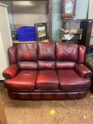Ox blood red leather three seater sofa, with additional cushions.