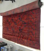 Vintage Afghan tribal wool rug with a deep red field and navy blue accents, featuring a repeating