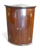 A Georgian mahogany bow front hanging corner cupboard with inlay decoration, H100cm x W70cm x D50cm.