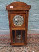 Oak cased mechanical wall clock, key and pendulum present.