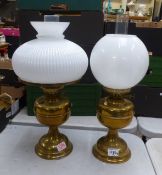Two brass oil lamps (bases match), with glass chimneys and milk glass shades, overall height 51cm (
