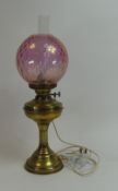 Brass oil lamp with ornate cranberry glass shade, converted to electric. (H: 56.5cm)