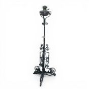 Benson-style wrought iron and copper standard oil lamp, on a tripod base with ornate curved feet.