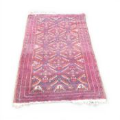 100% Wool Pile rug with recurring abstract pattern of reds and navy's. (L: 180cm x W: 90cm)