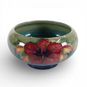 Moorcroft footed bowl in the Hibiscus pattern on green to blue graduating ground. (D: 16cm)