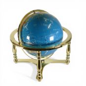 A decorative gemstone world globe featuring polished blue sphere, with land masses depicted by