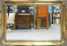 A large, rectangular wall mirror, in an ornate, decorative gilded frame. (H: 65cm x W: 90.5cm)