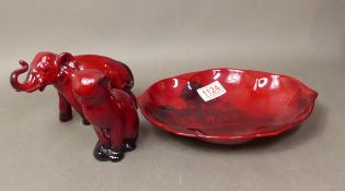 Three pieces of Royal Doulton Flambe, a shaped dish signed Noke, a small seated cat and an elephant,
