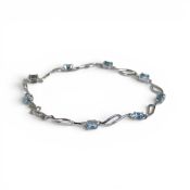 9ct white gold tennis bracelet set with eight light blue stones, 4.7g.