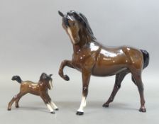 Royal Doulton Brown Gloss Horse Tucked up leg model no:-DA 51 together with a standing foal.