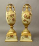 Pair of Austrian blush ivory twin handled vases raised on square plinths, height 27cm (2).