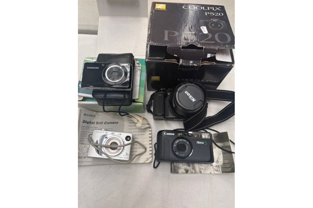 A group of 4 cameras, including the Samsung Pl100 Camera in its original box with accessories, the